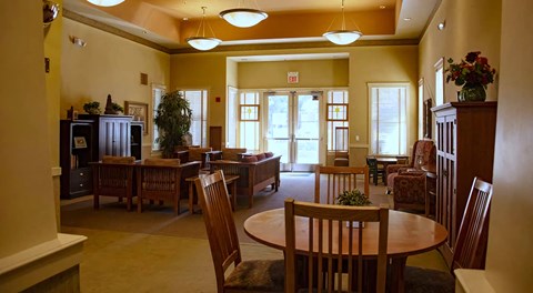 A room with a table and chairs in the foreground and a doorway in the background.