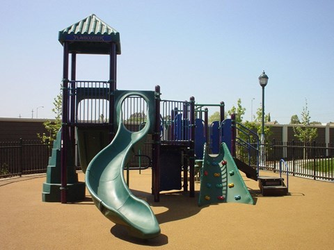 A playground with a green slide and a blue tower.