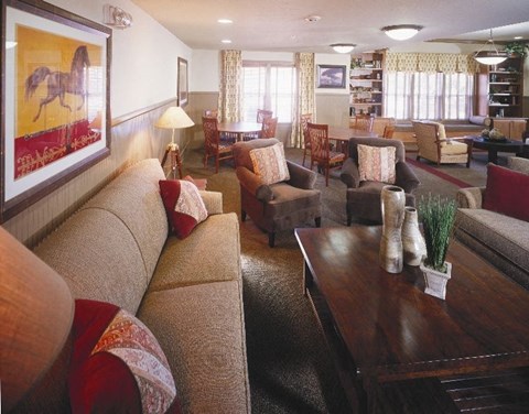 A living room with a brown couch and a painting of a horse on the wall.