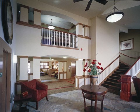 A living room with a red chair and a table with flowers on it.