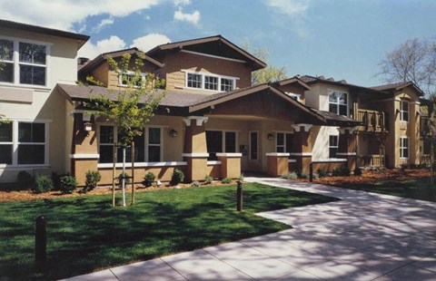 A row of houses with a sidewalk in front.