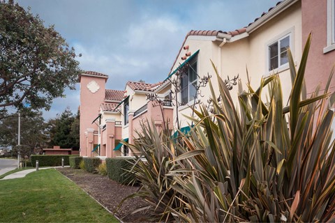 A pink building with a clock tower and a green lawn in front.