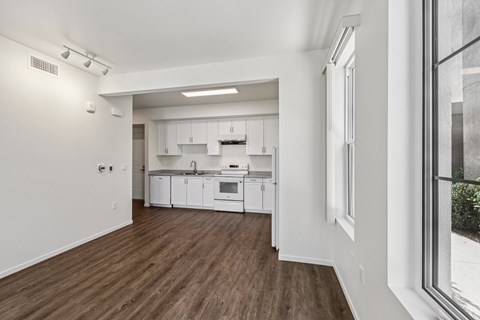 A kitchen with white cabinets and a wooden floor.