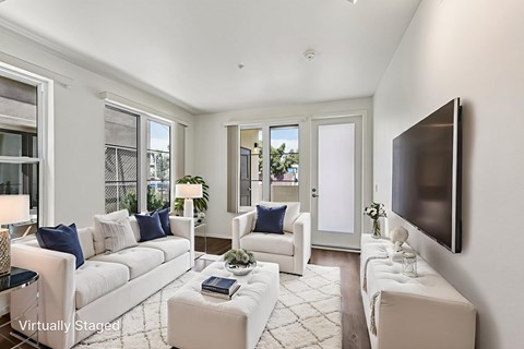 A living room with white furniture and a flat screen TV mounted on the wall.