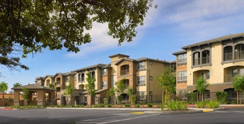 A row of modern apartment buildings with trees in the foreground.
