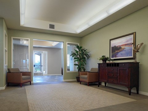 A living room with a painting on the wall and a plant on the side table.