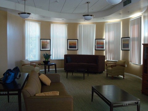 A living room with a brown couch and a blue backpack on a table.