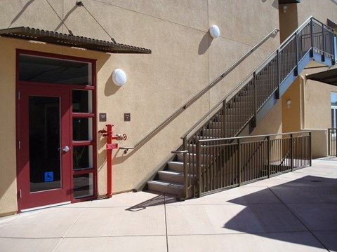 A red door with a glass window is on the left side of a staircase.