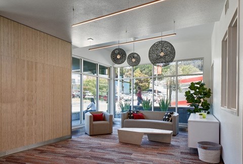 A waiting area with a couch, chair, and decorative hanging lamps.