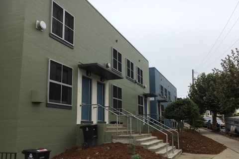 A grey building with a blue door and steps leading up to it.