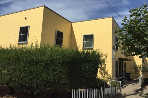 A yellow building with a black trash can in front.