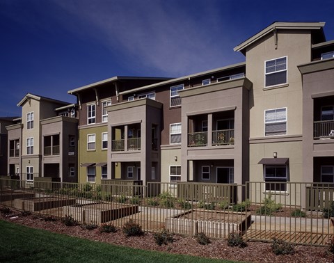 A row of modern apartment buildings with green lawns in front.
