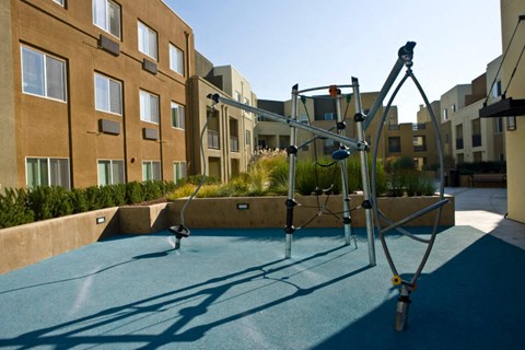 A playground with a slide and swings in front of apartment buildings.