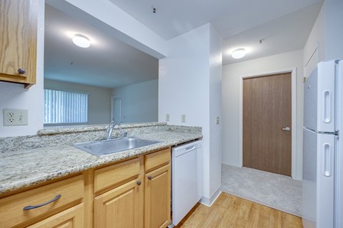 A kitchen with a sink, refrigerator, and wooden cabinets.
