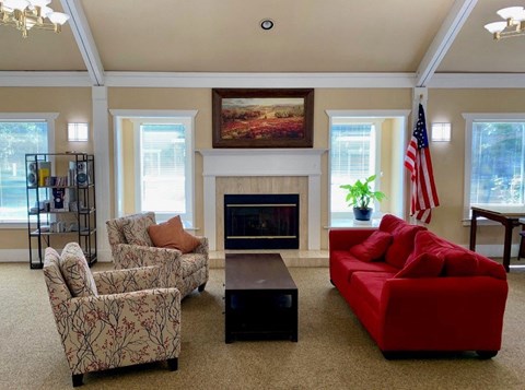 A living room with a fireplace, chairs, and a red couch.