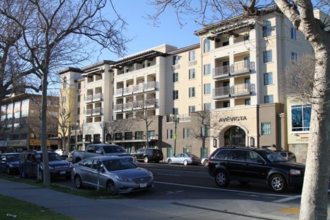 A street view of a building with cars parked in front.