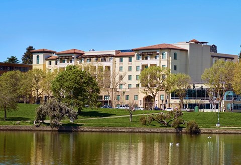 A large building with a red roof is situated next to a body of water.