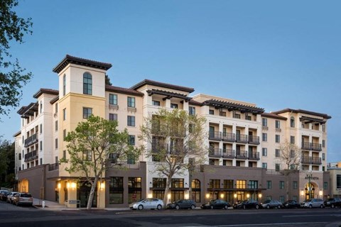 A large apartment building with a parking lot in front.