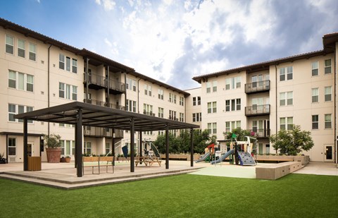 A playground area is located in front of apartment buildings.