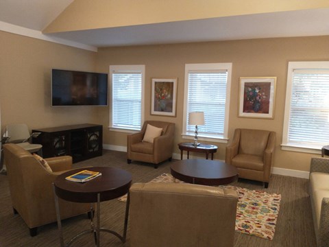 A living room with a brown couch, a brown chair, a brown coffee table, and a flat screen TV mounted on the wall.