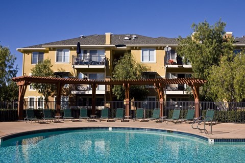 A large yellow building with a pool in front.