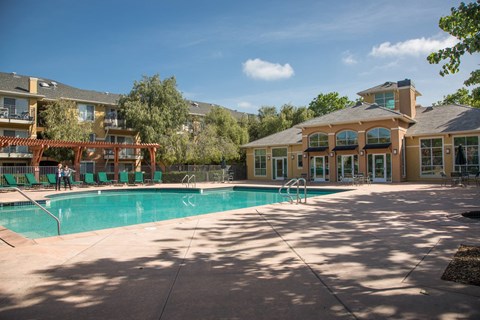 A large swimming pool in front of a building with a sunny day.