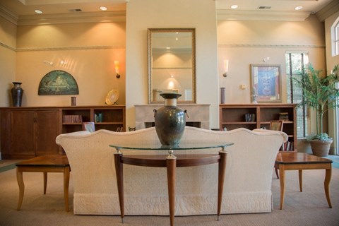 A living room with a white sofa and a glass table in the middle.