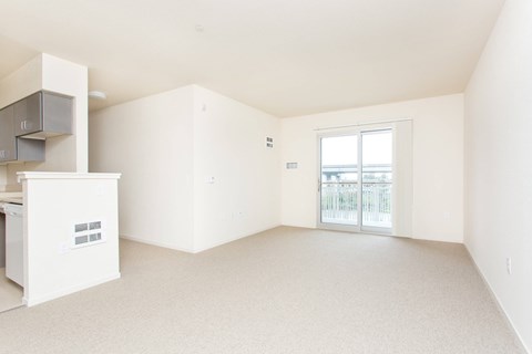A white kitchen with a refrigerator, cabinets, and a window.