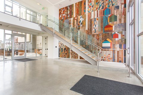 A staircase with a glass railing and a mosaic wall on the side.