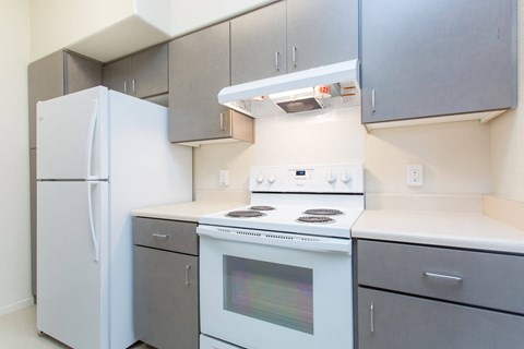 A white refrigerator stands next to a stove in a kitchen.