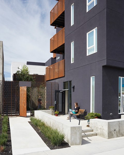 A woman sits on a bench outside a modern building.