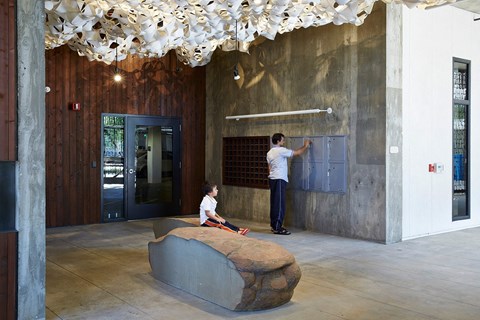 A man is painting a wall in a room with a concrete floor and a wooden ceiling.
