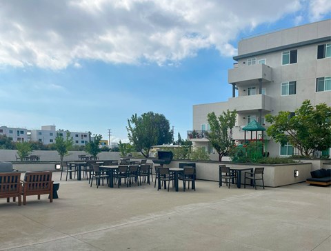 A patio with tables and chairs is surrounded by a building.