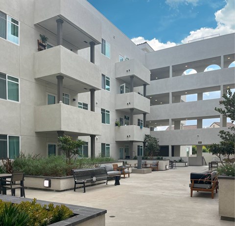 A courtyard with benches and plants in front of a concrete building.