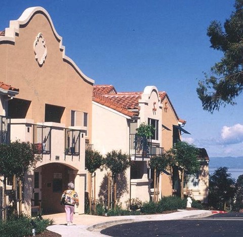 A woman is walking in front of a building with a clock on it.