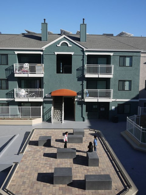 A courtyard with a few people sitting on the benches.