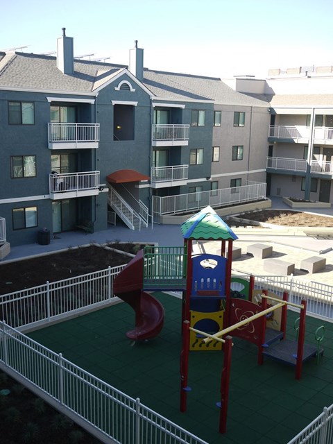 A playground with a red slide and a green roofed structure.