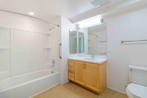 A white bathroom with a wooden cabinet and a white toilet.