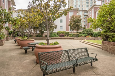 A park with benches and trees in front of a building.