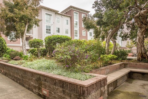 A brick wall with a small pond in front of a building.