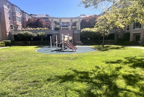 A playground with a slide and swings in a grassy area.