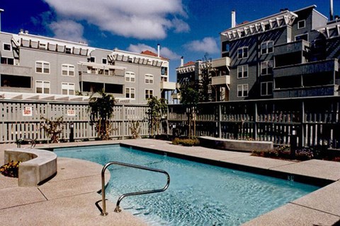 A small pool with a metal ladder sits in front of apartment buildings.