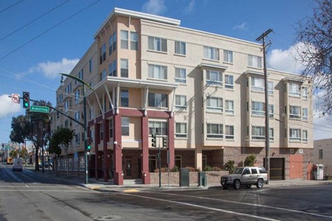 A large building with a red and beige facade is situated on a street corner.