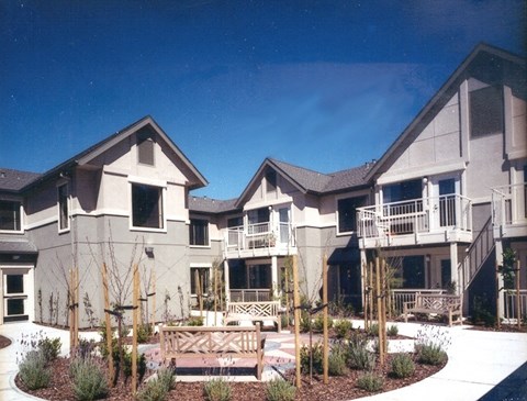 A large house with a balcony and a small garden in front.