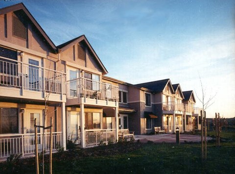 Apartment complex with balconies and a small garden in front.