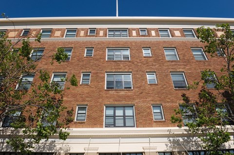 A red brick building with a white trim around the windows and a white awning below the windows.