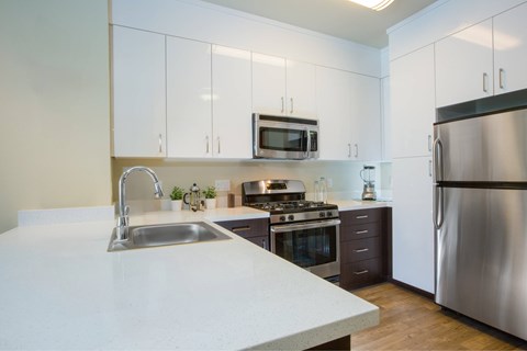 A modern kitchen with a stainless steel refrigerator and a white countertop.