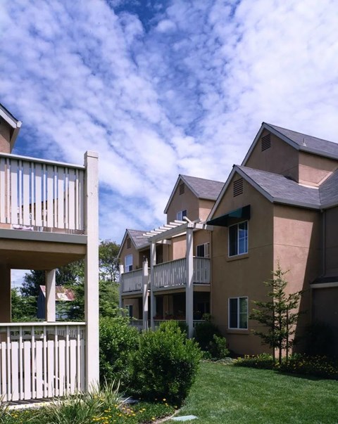 Apartment buildings with balconies and greenery in front.