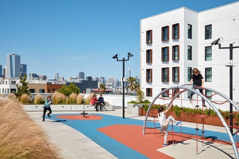 A playground with a slide and swings in front of a white building.
