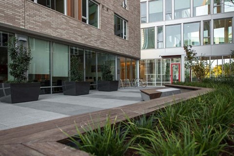 A modern building with a red door and a wooden walkway in front.